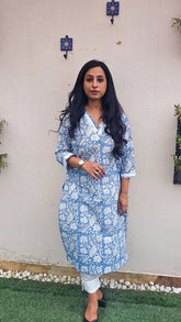 Woman wearing a blue floral with bird motifs hand block print kurta with white pants. Its a pure cotton kurta.