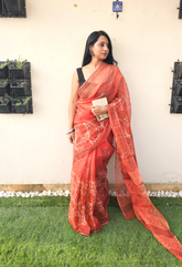 Elegant orange handloom saree with intricate paisley and floral motifs, styled with a sleeveless black blouse- lightweight daily wear in traditional Indian design.