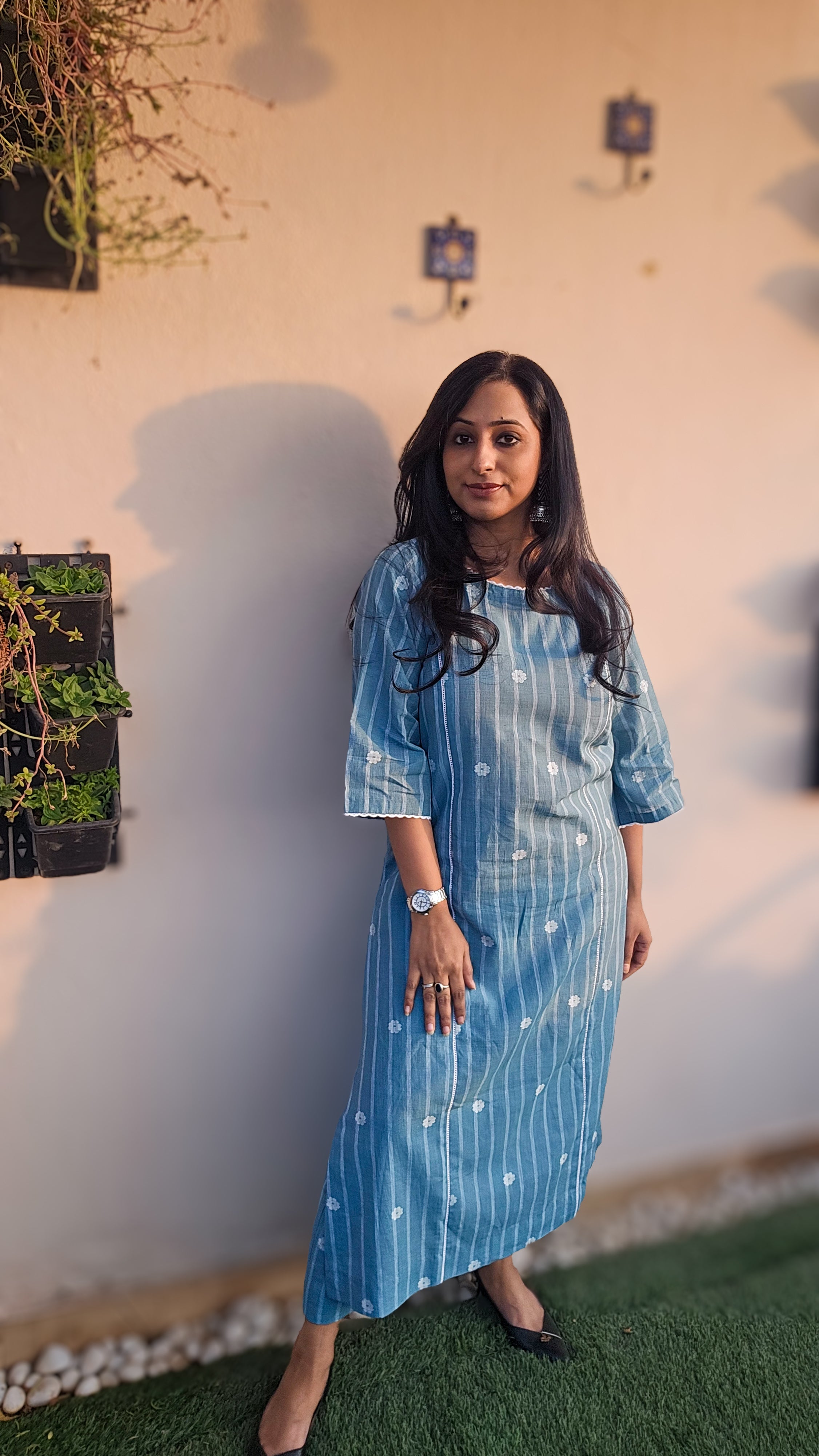 Woman in a blue dress standing outdoors with a neutral background
