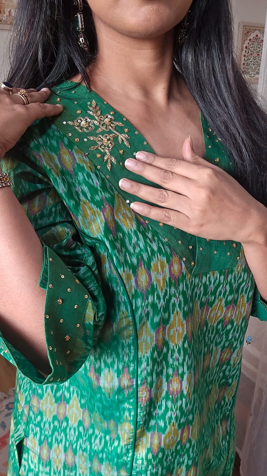 Person wearing a green patterned dress with floral embroidery