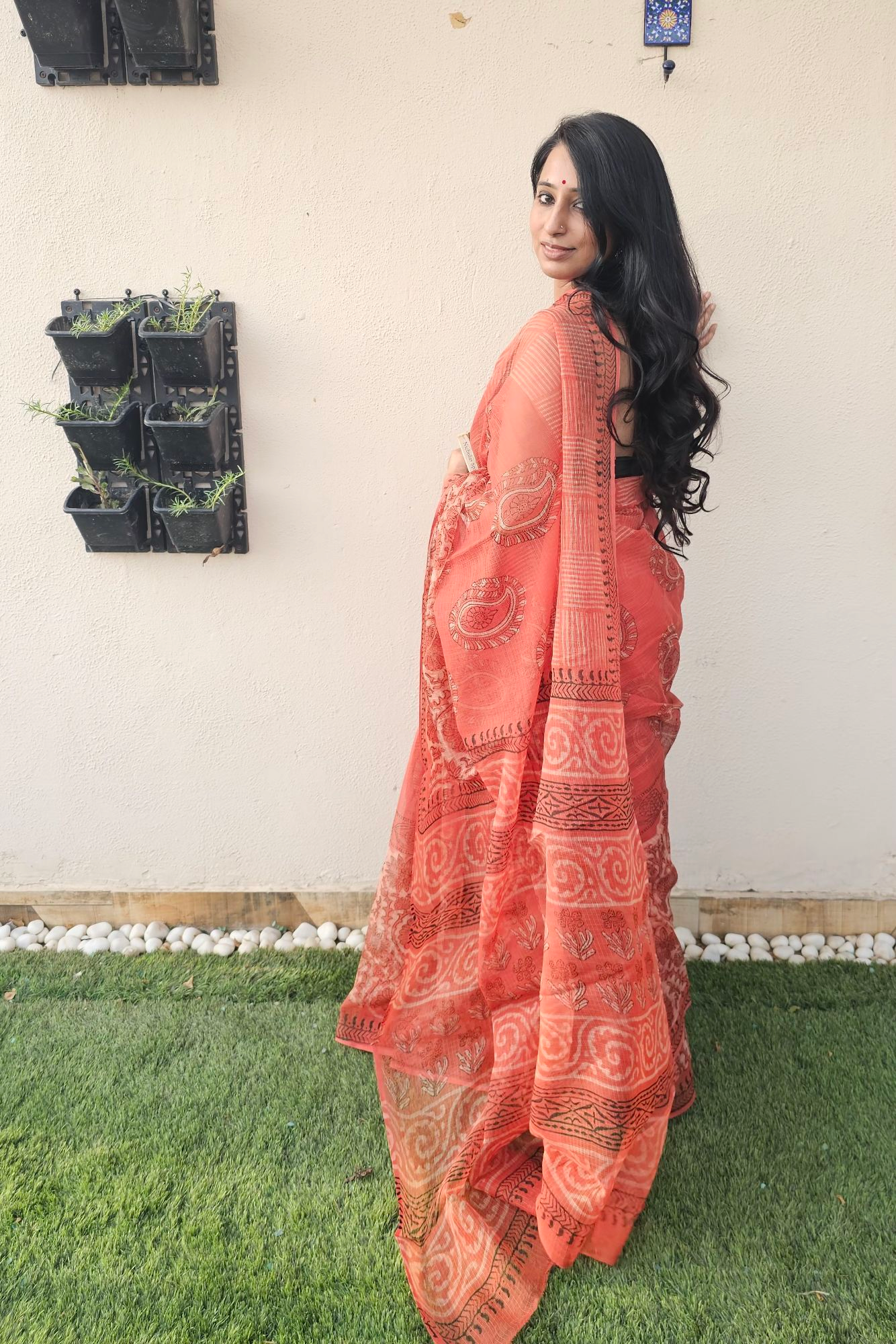 Elegant orange handloom saree with intricate paisley and floral motifs, styled with a sleeveless black blouse- lightweight daily wear in traditional Indian design.
