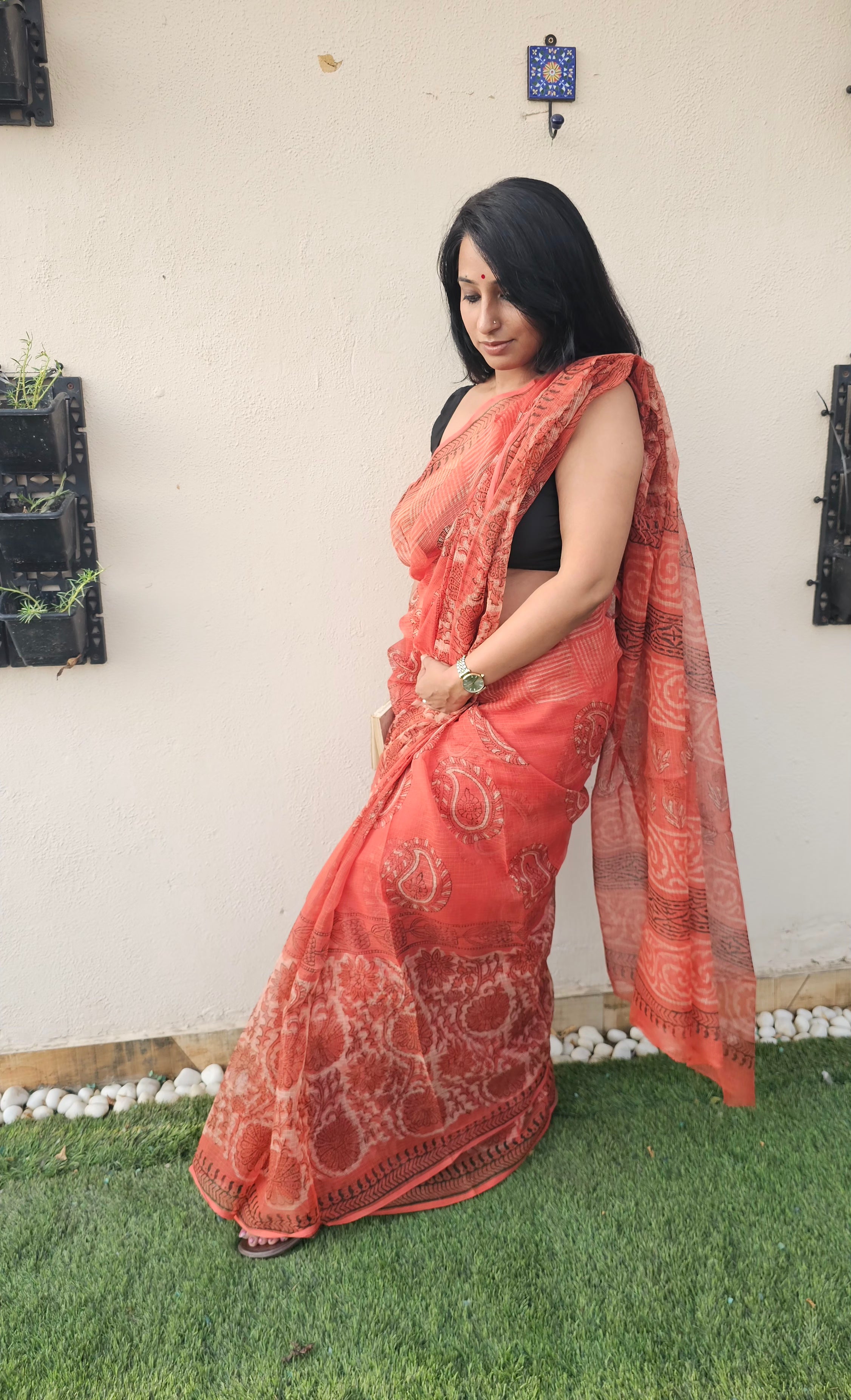 Elegant orange handloom saree with intricate paisley and floral motifs, styled with a sleeveless black blouse- lightweight daily wear in traditional Indian design.