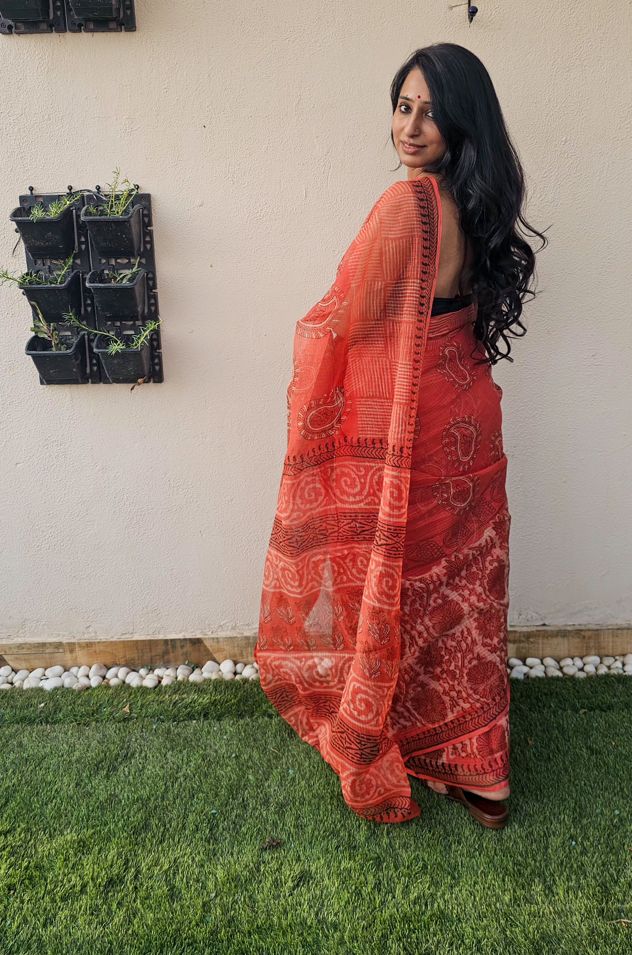 Elegant orange handloom saree with intricate paisley and floral motifs, styled with a sleeveless black blouse- lightweight daily wear in traditional Indian design.